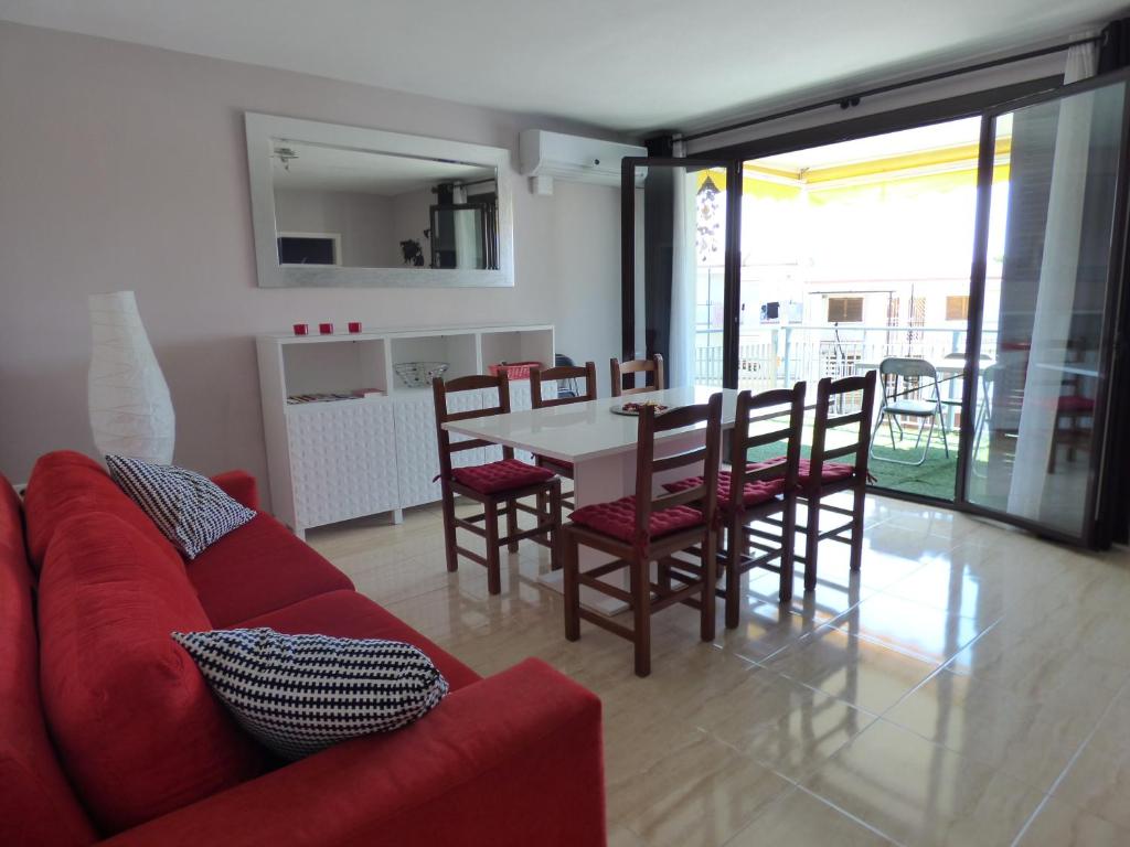 a living room with a red couch and a table and chairs at Reus Mediterrani in Cambrils