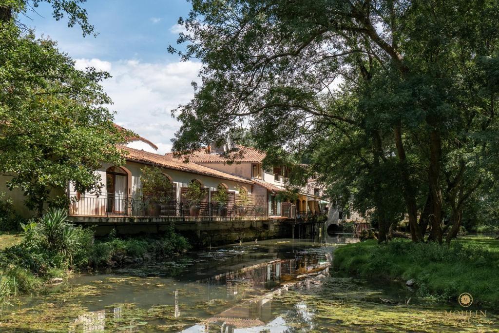 un pont sur une rivière dans un parc dans l'établissement Moulin du Val de Seugne, à Mosnac