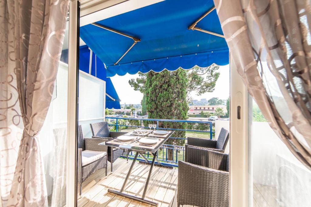 カーニュ・シュル・メールにあるL'Ascot Appartement, plages à 300m, vue hippodromeのパティオ(テーブル、椅子、青い傘付)