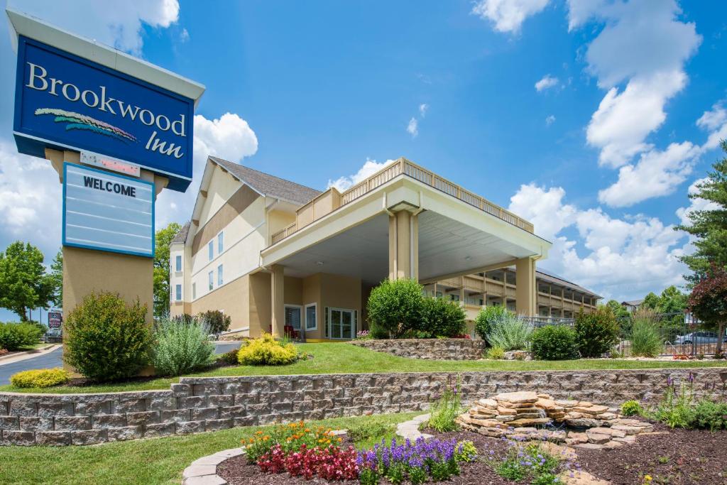 a front view of a hotel with a sign and flowers at Brookwood Inn Branson in Branson