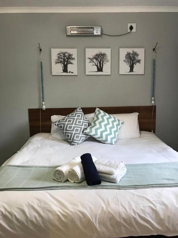 a bed with two towels and three pictures on it at Celtis Lane Guest House in Boksburg