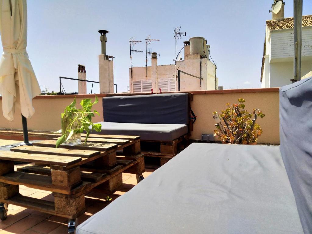 een balkon met een bank en tafels op een dak bij Suitur Atico Sitges Centro in Sitges