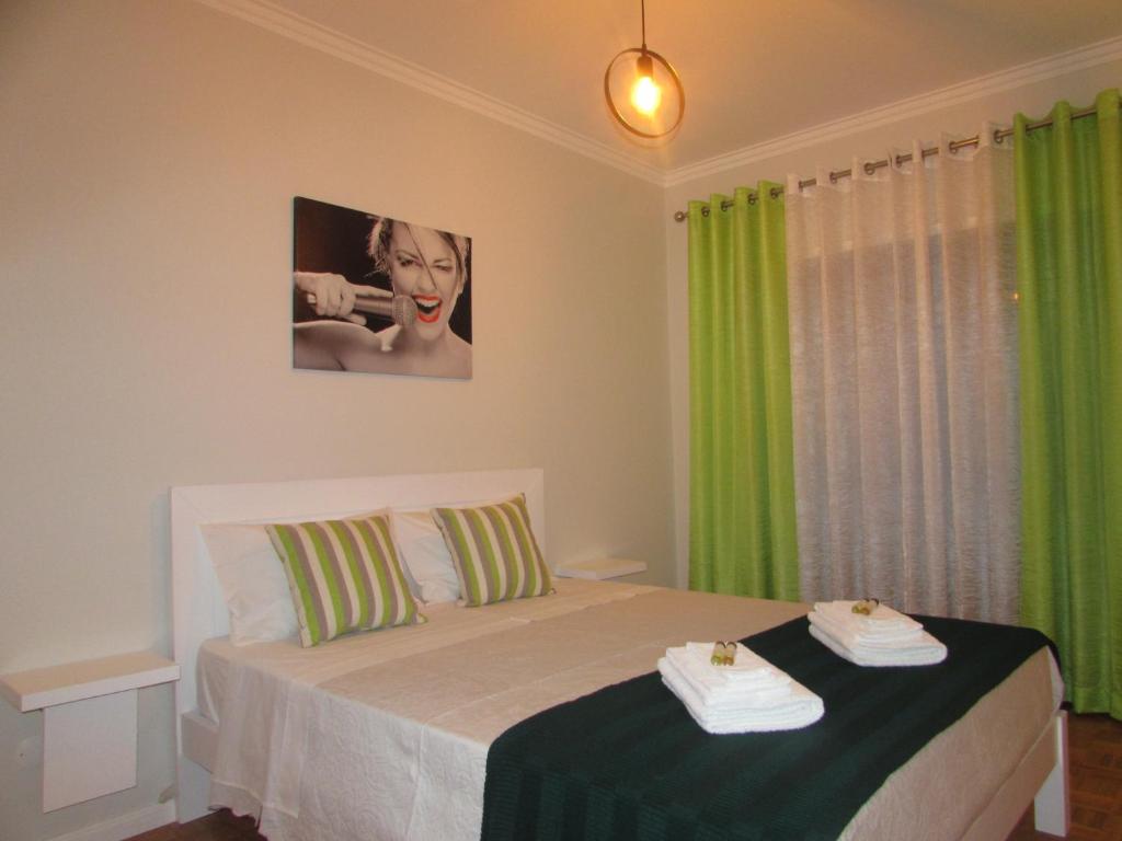 Schlafzimmer mit einem Bett und grünen Vorhängen in der Unterkunft Ar Puro III in Viana do Castelo