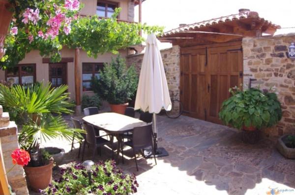 un patio con mesa, sombrilla y plantas en Hotel Rural La Veleta, en Murias de Rechivaldo