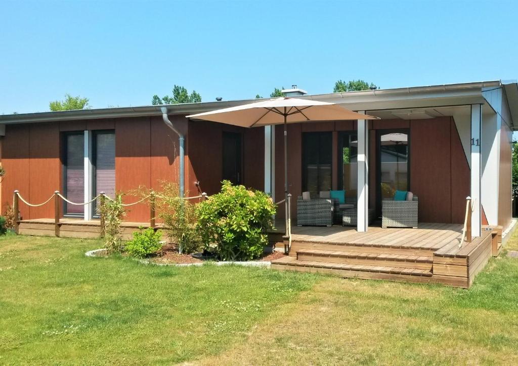 ein Haus mit einer Holzveranda und einem Sonnenschirm in der Unterkunft Ferienhaus Chrissy in Loissin