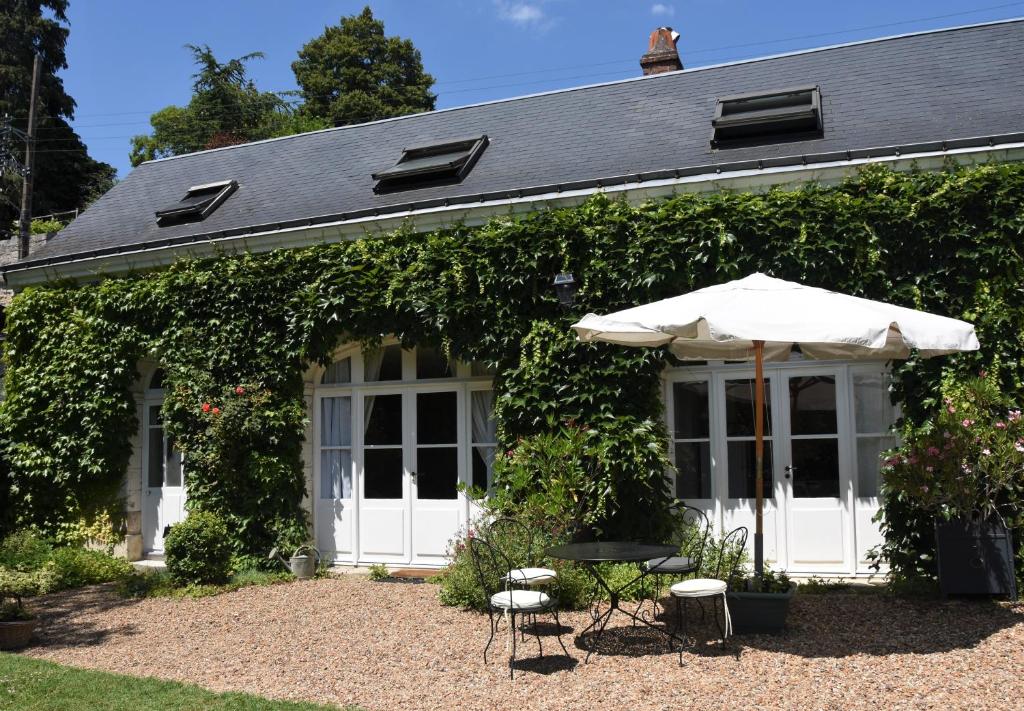 un parasol et des chaises devant une maison dans l'établissement Le clos des Acanthes, à Vouvray