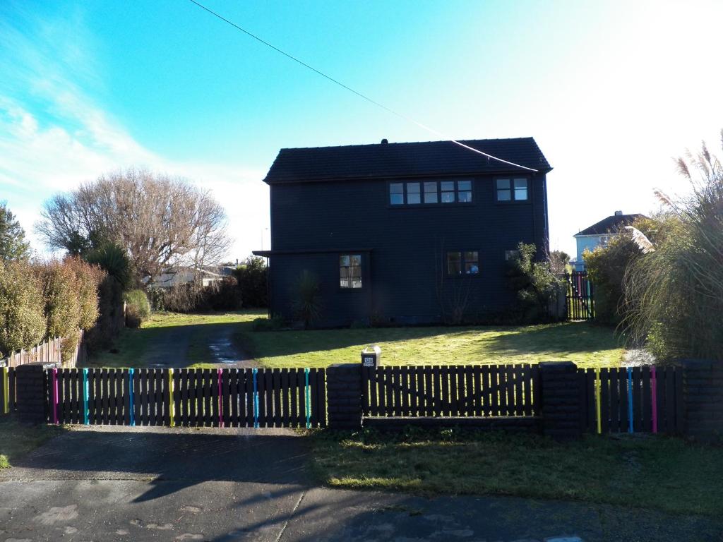 een zwart huis met een hek ervoor bij The Crawford's in Invercargill