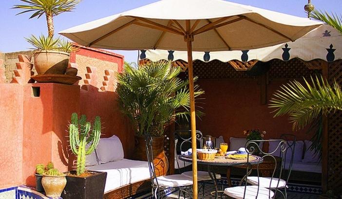 un patio con sombrilla, mesa y sillas en Riad Bab Chems, en Marrakech