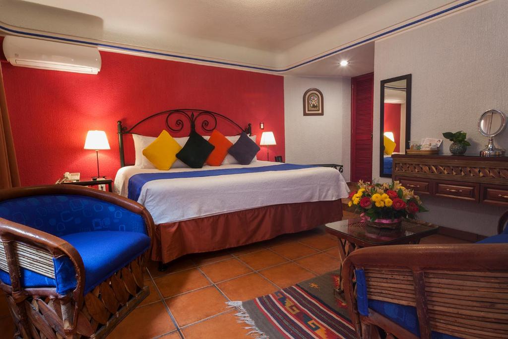 um quarto com uma cama e uma parede vermelha em Hotel Boutique Parador San Miguel Oaxaca em Oaxaca de Juárez