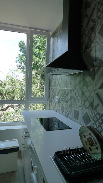 a kitchen with a counter with a sink and two windows at Lei Home in Cascais