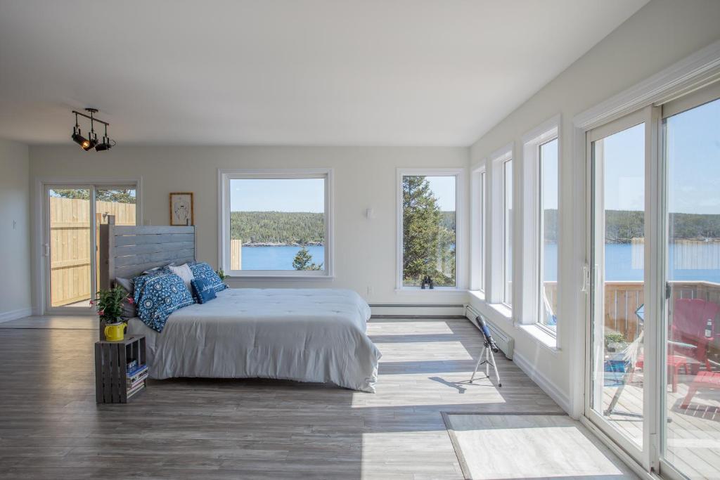 a white bedroom with a bed and large windows at Whale House Guest House in Mobile