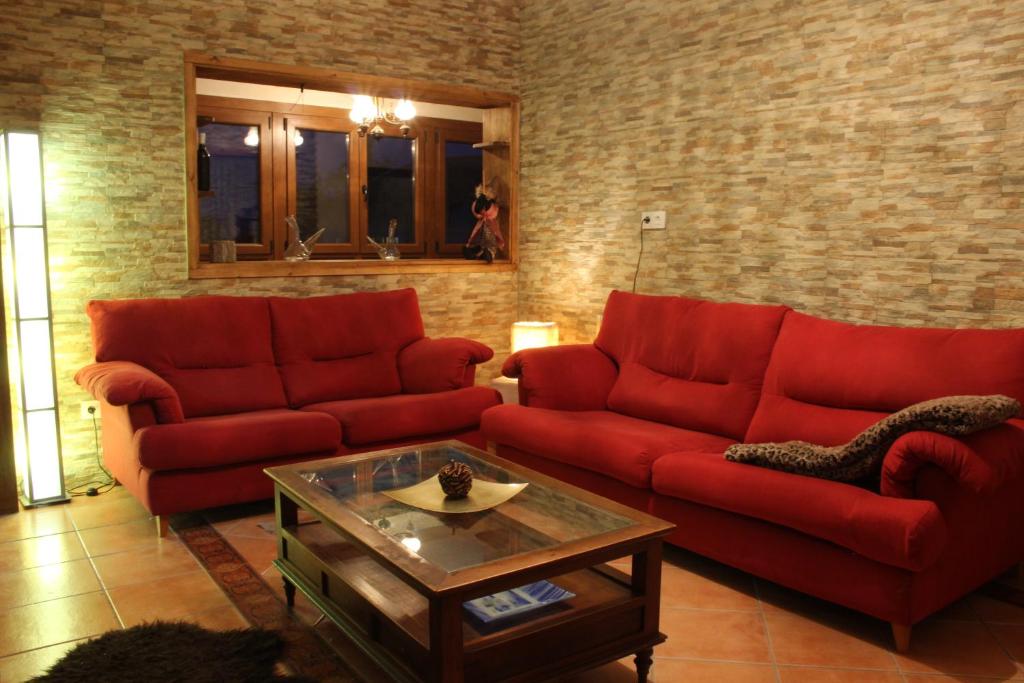 una sala de estar con 2 sofás rojos y una mesa. en Casa do Bouza Vello, en Sober