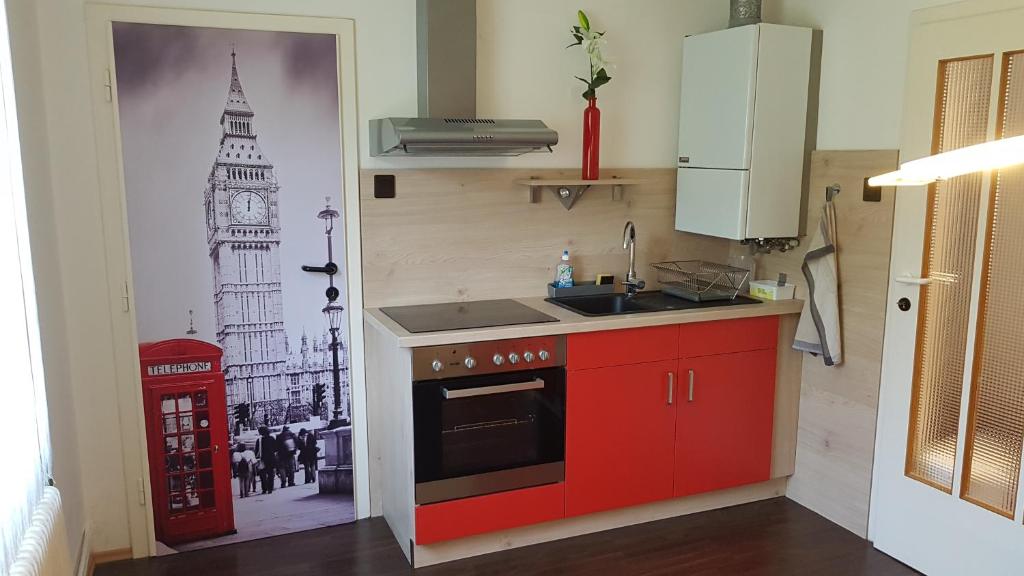 a kitchen with a red cabinet and a picture of the clock tower at Garden Apartment Donau-City (P&R) in Vienna