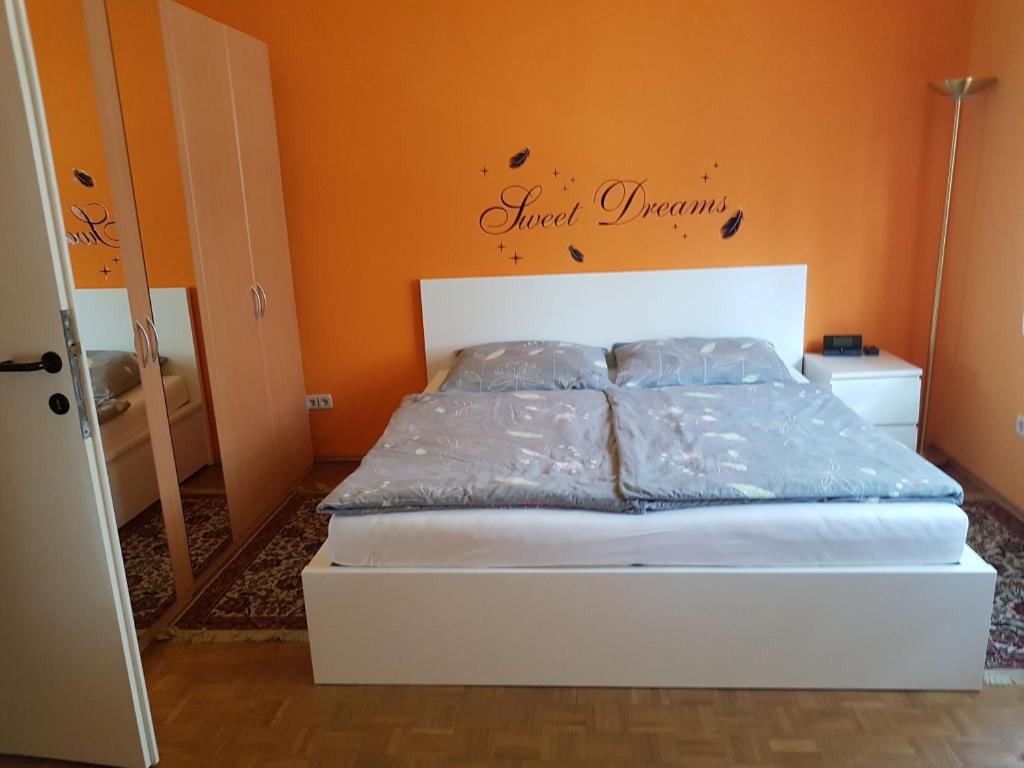 a bed in a bedroom with an orange wall at Garden Apartment Donau-City (P&R) in Vienna