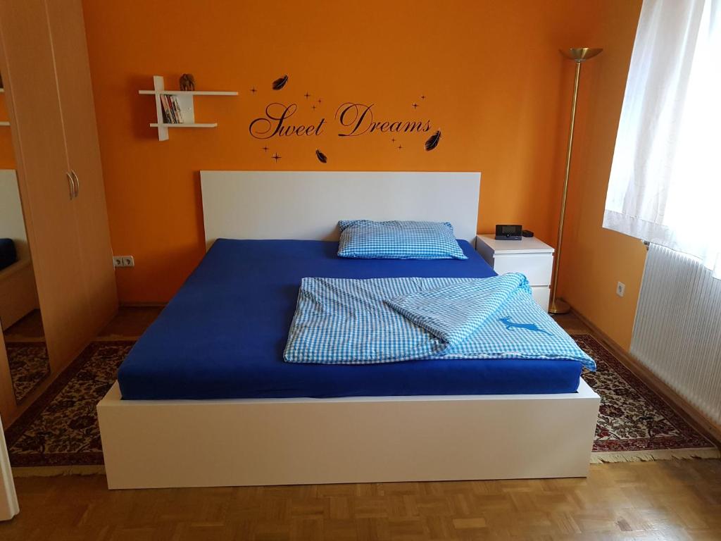 a bedroom with a bed with blue sheets and orange walls at Garden Apartment Donau-City (P&R) in Vienna