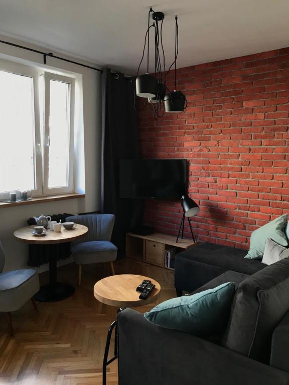 een woonkamer met een bank en een bakstenen muur bij Warszawa Hoża in Warschau