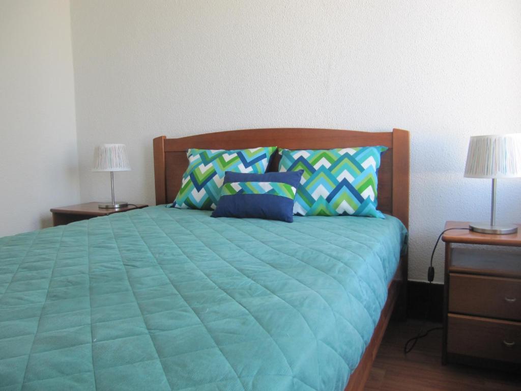 ein Bett mit einer grünen Bettdecke, zwei Nachttischen und zwei Lampen in der Unterkunft Troia Mare Nostrum in Troia