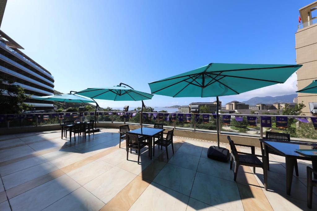 un patio con tavoli, sedie e ombrelloni di Pinxiayuan Apartment in Lvcheng Resort a Zhoushan