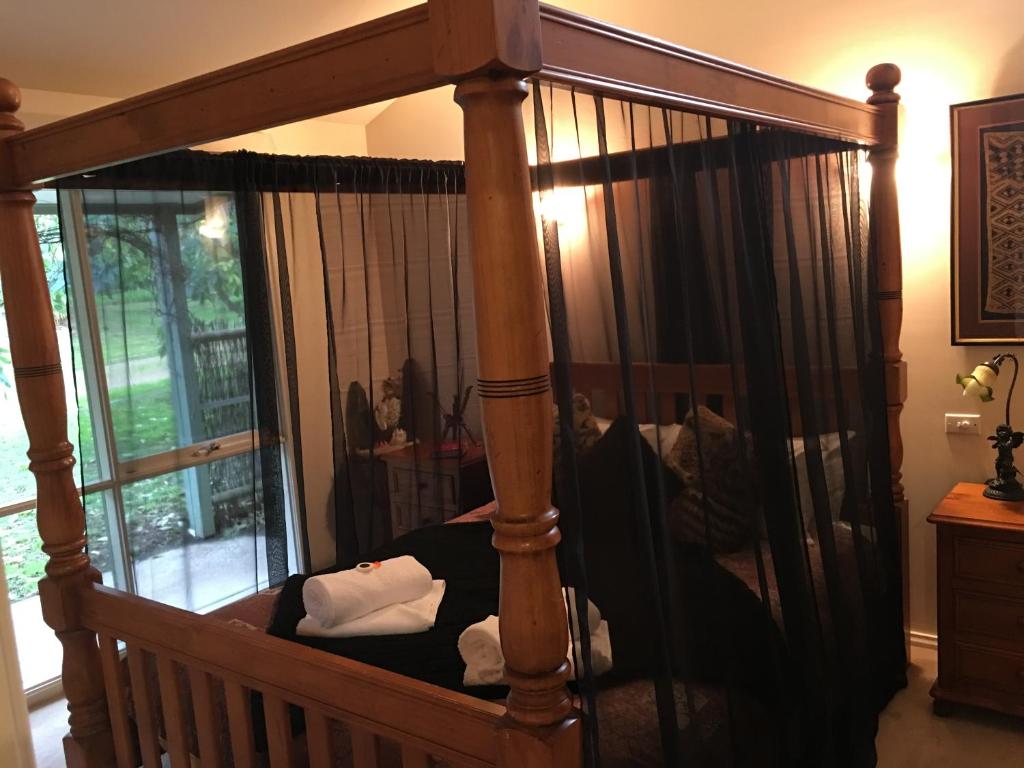 a wooden canopy bed in a room with a window at Weeroona Bed And Breakfast in Rye