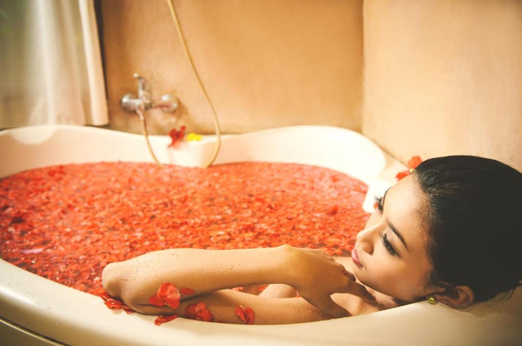 a woman laying in a bath tub filled with red peppers at Sri Phala Resort & Villa in Sanur