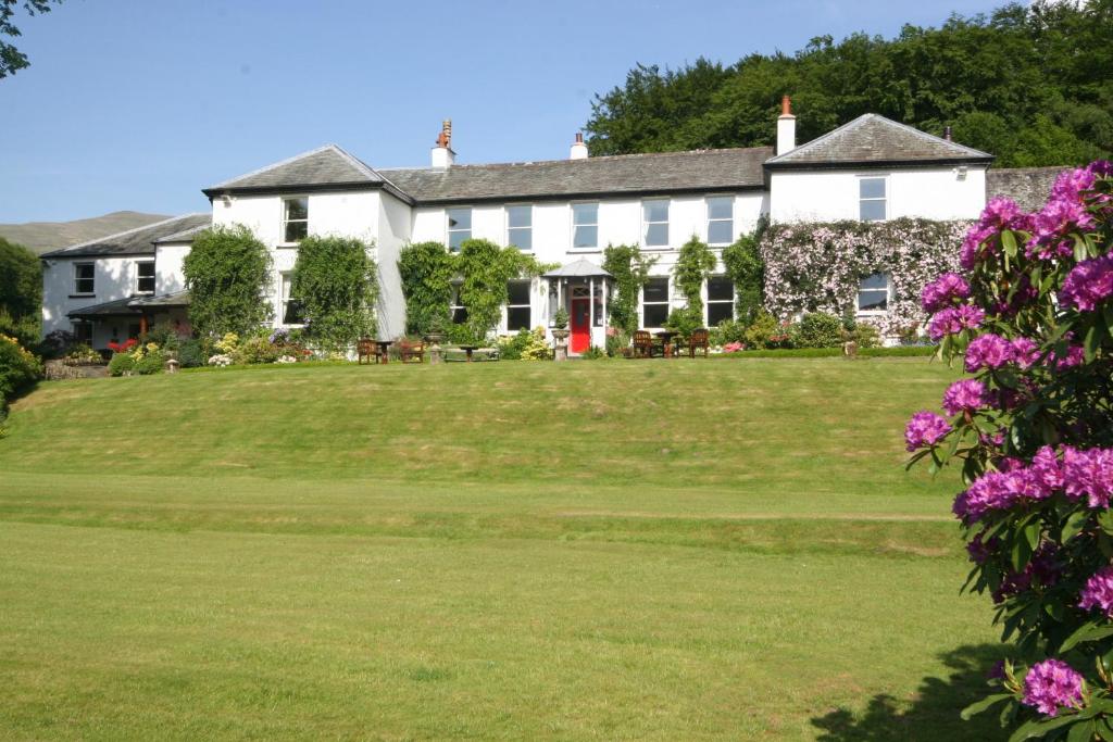 uma grande casa branca com um jardim verde em Dale Head Hall Lakeside Hotel em Keswick