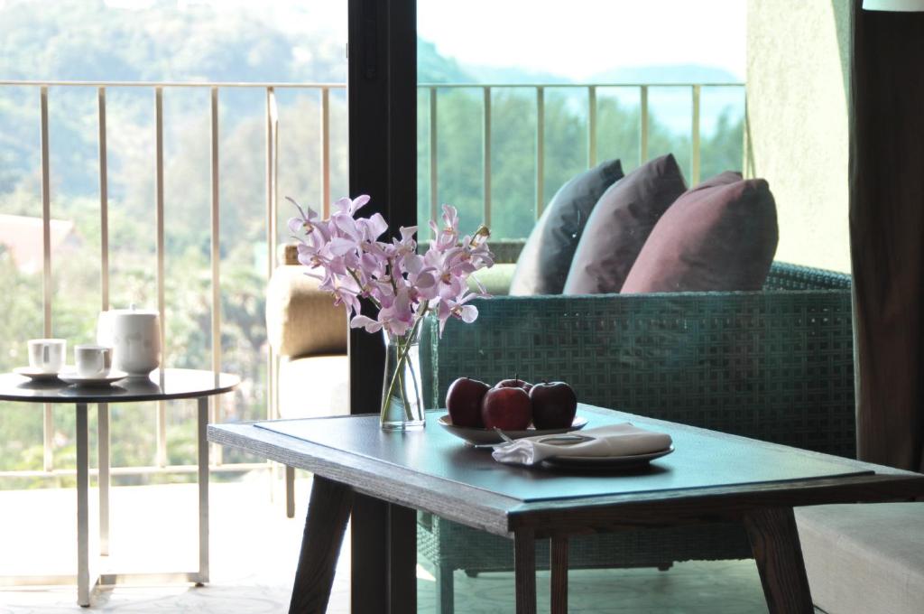 a table with a vase of flowers on a balcony at Sunsuri Phuket - SHA Plus in Nai Harn Beach