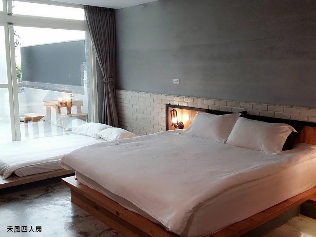 a bedroom with two beds and a large window at Hotian Inn in Donggang