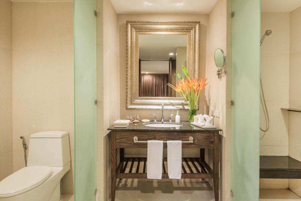 a bathroom with a sink and a mirror and a toilet at Sunsuri Phuket - SHA Plus in Nai Harn Beach