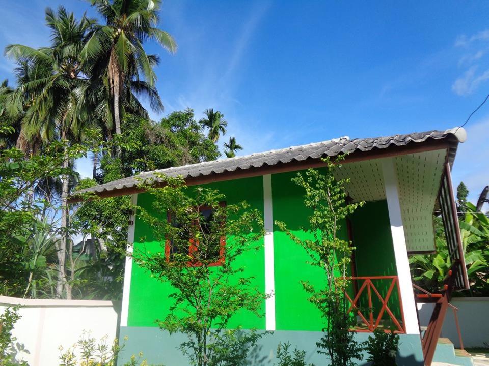 a green house with a palm tree in the background at Sarm Mork Guest House in Mae Hong Son