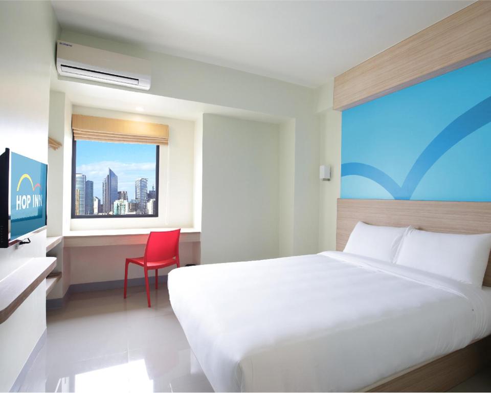a bedroom with a bed and a desk and a window at Hop Inn Hotel Ermita Manila in Manila
