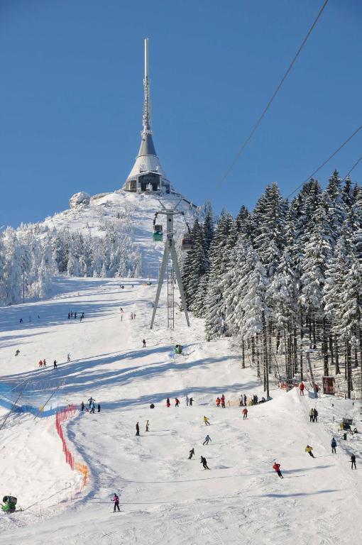 a group of people skiing down a ski slope with a ski lift at Hotel Ještěd in Liberec