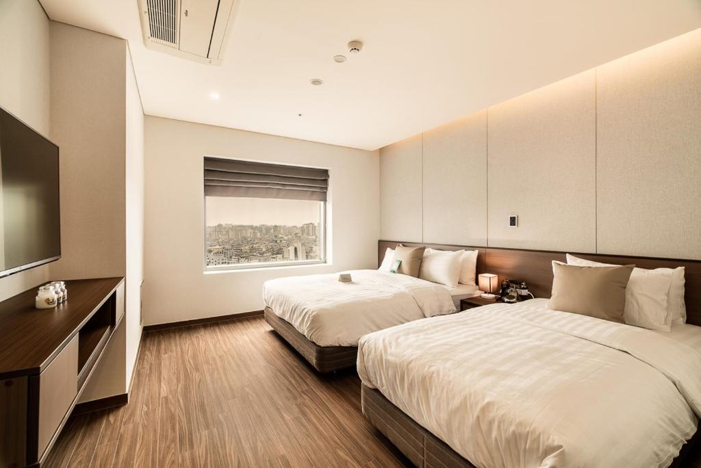 a hotel room with two beds and a flat screen tv at WD Hotel in Seoul