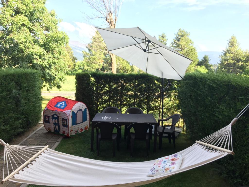a hammock in a garden with a table and a tent at Nature Appartements Font Romeu in Font-Romeu