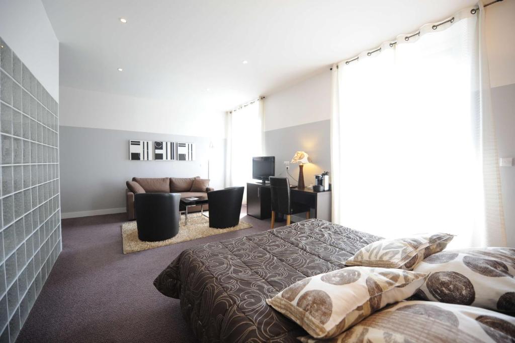 een slaapkamer met 2 bedden en een woonkamer bij Hôtel Continental Pau Centre in Pau