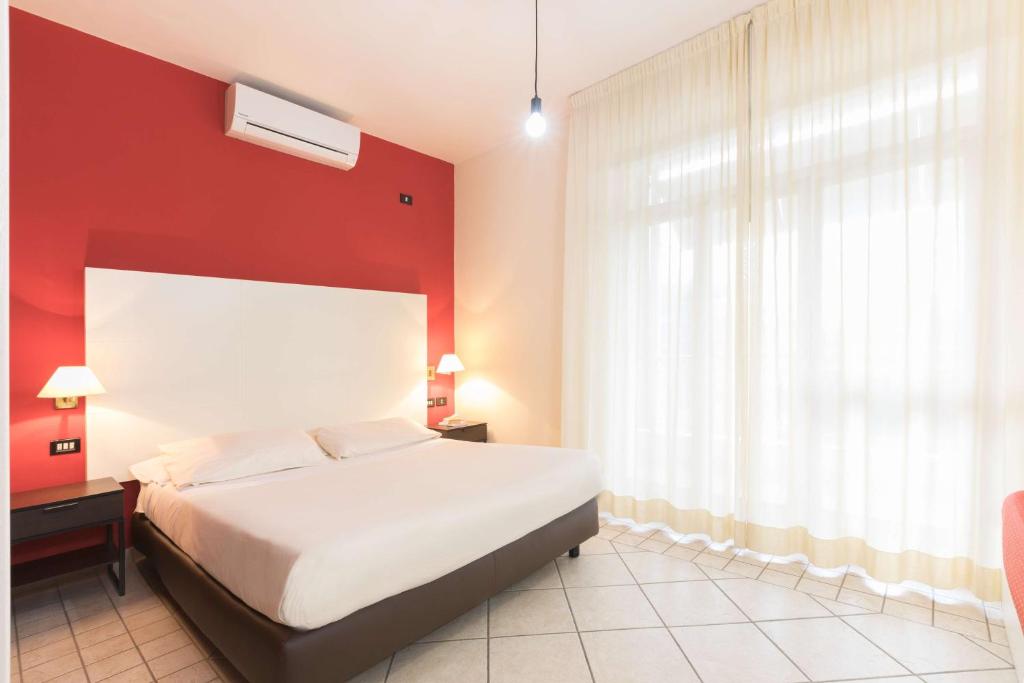 una camera con un letto bianco e una parete rossa di Hotel La Baia a Bari