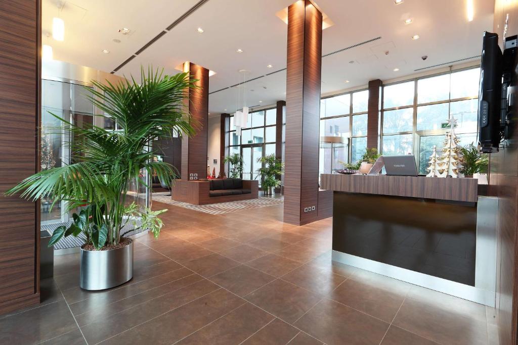 un hall avec des palmiers dans un bâtiment dans l'établissement Best Western Plus Hotel Monza e Brianza Palace, à Cinisello Balsamo
