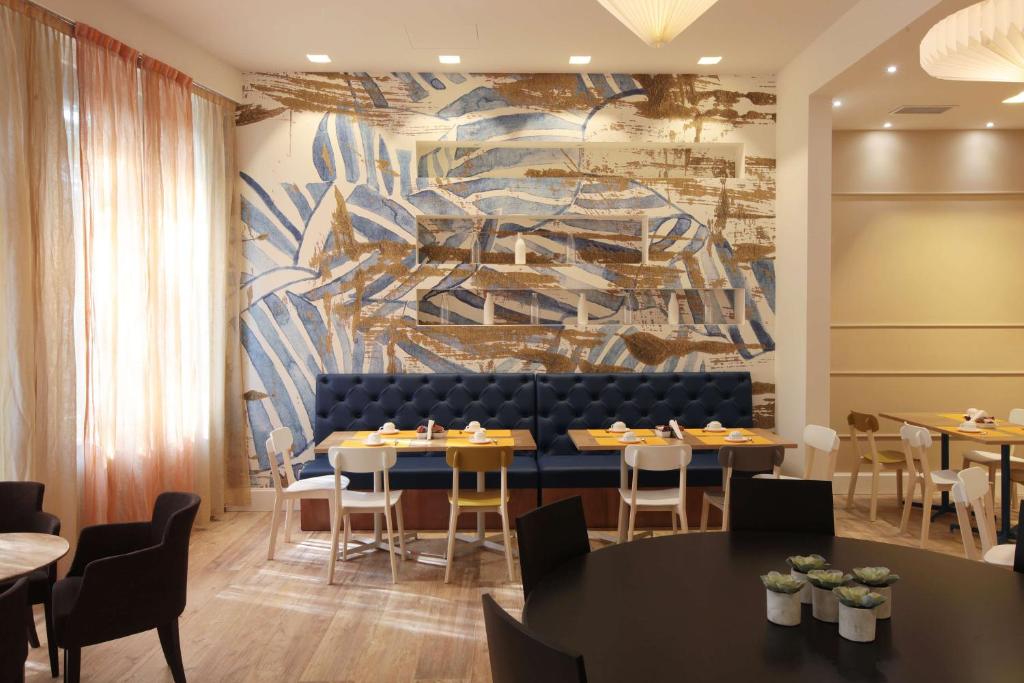 uma sala de jantar com mesas e cadeiras e um mural em Best Western Hotel Piemontese em Bérgamo