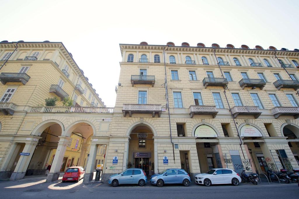 duży budynek z samochodami zaparkowanymi przed nim w obiekcie Best Western Crystal Palace Hotel w Turynie