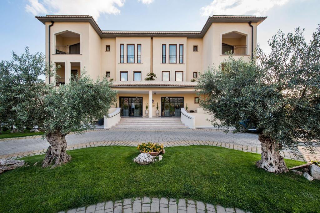 un grand bâtiment avec des arbres devant lui dans l'établissement Best Western Premier Villa Fabiano Palace Hotel, à Rende