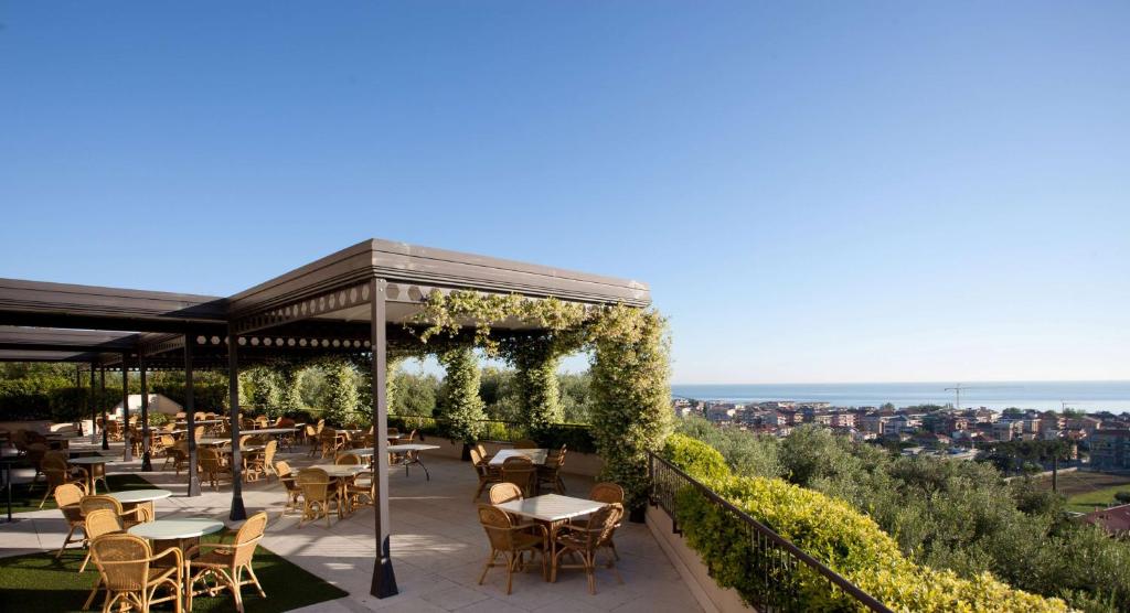 a patio area with tables, chairs and umbrellas at Villa Maria Hotel & SPA in Francavilla al Mare