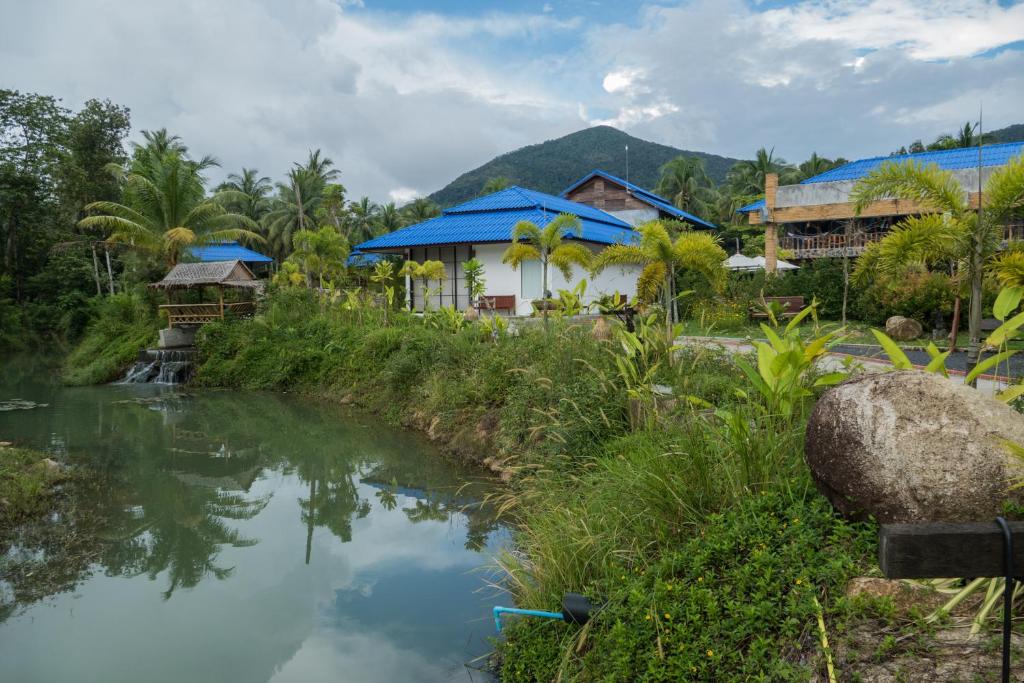 une rivière en face d'un village avec des maisons dans l'établissement Wonderland Healing Center, à Thongsala