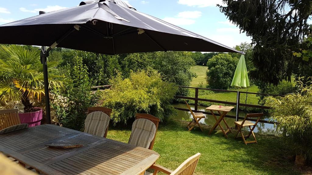 een tafel en stoelen met een parasol in de tuin bij La belmontaise in Beaumont-sur-Sarthe