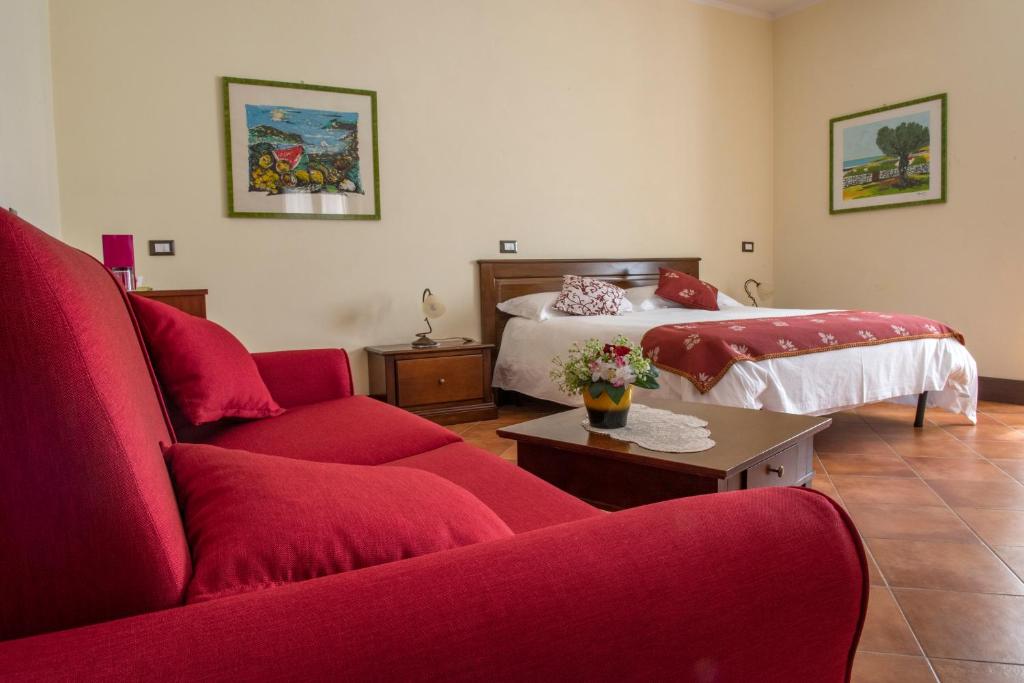 a living room with a red couch and a bed at Hotel Residenza Petra in Petralia Soprana