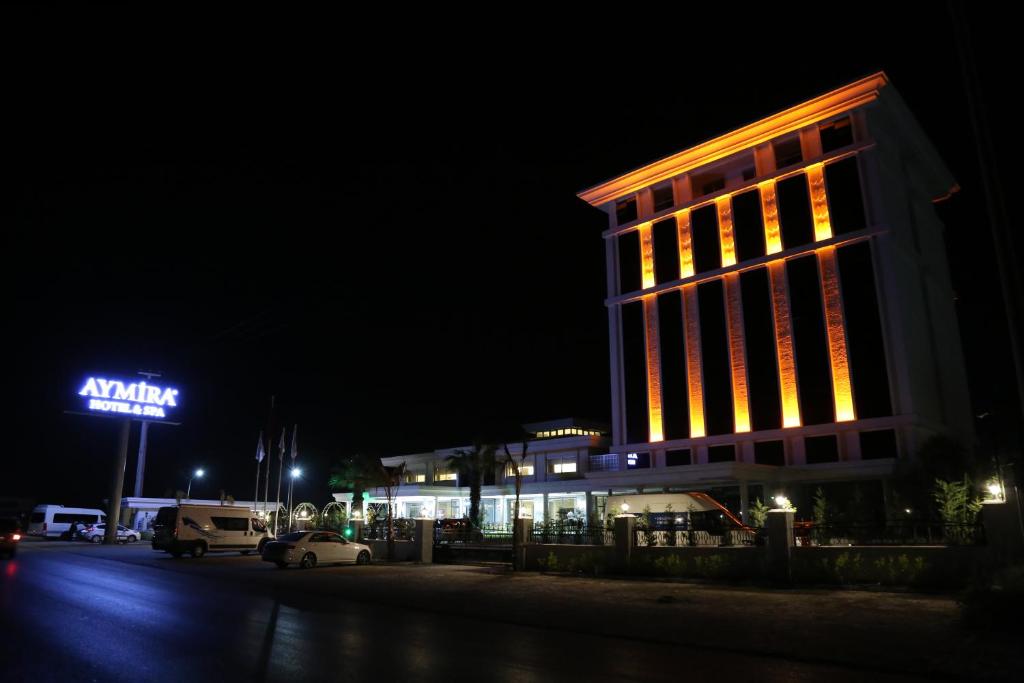 um edifício iluminado à noite com uma placa em AYMİRA HOTEL & SPA em Gereniz