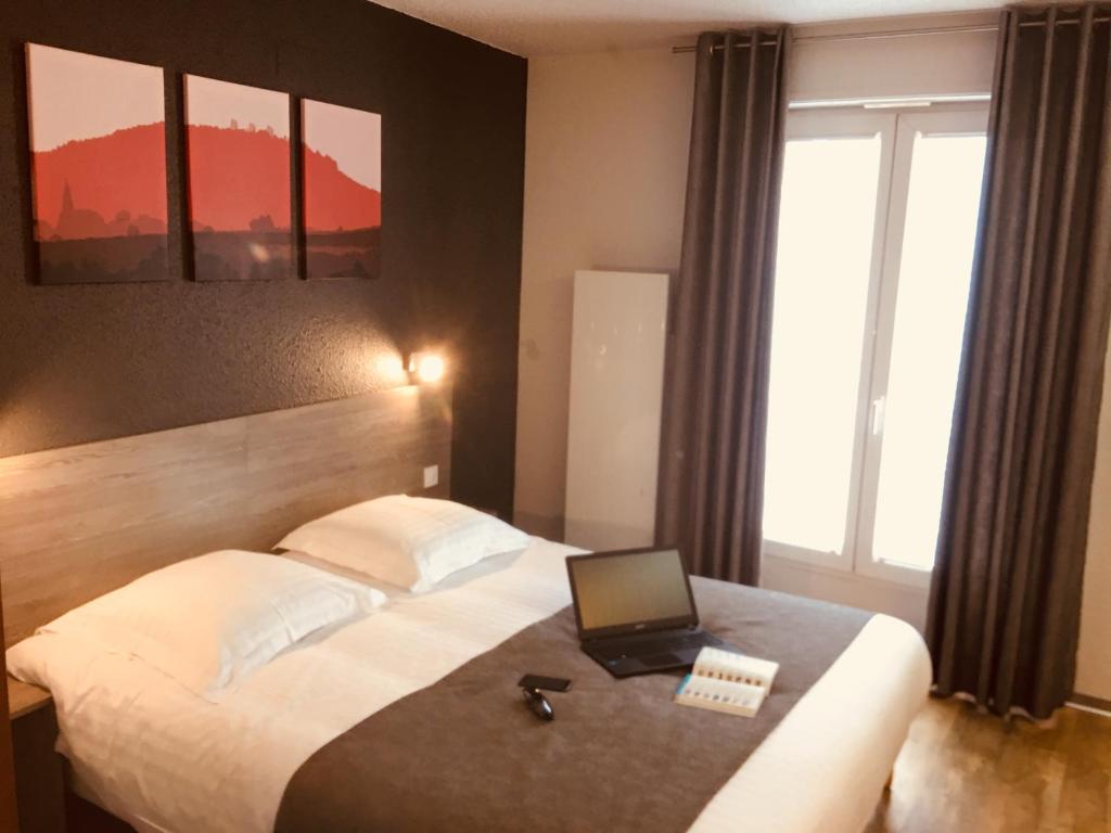 a hotel room with a bed with a laptop on it at Hotel Colmar Vignes Eguisheim in Eguisheim