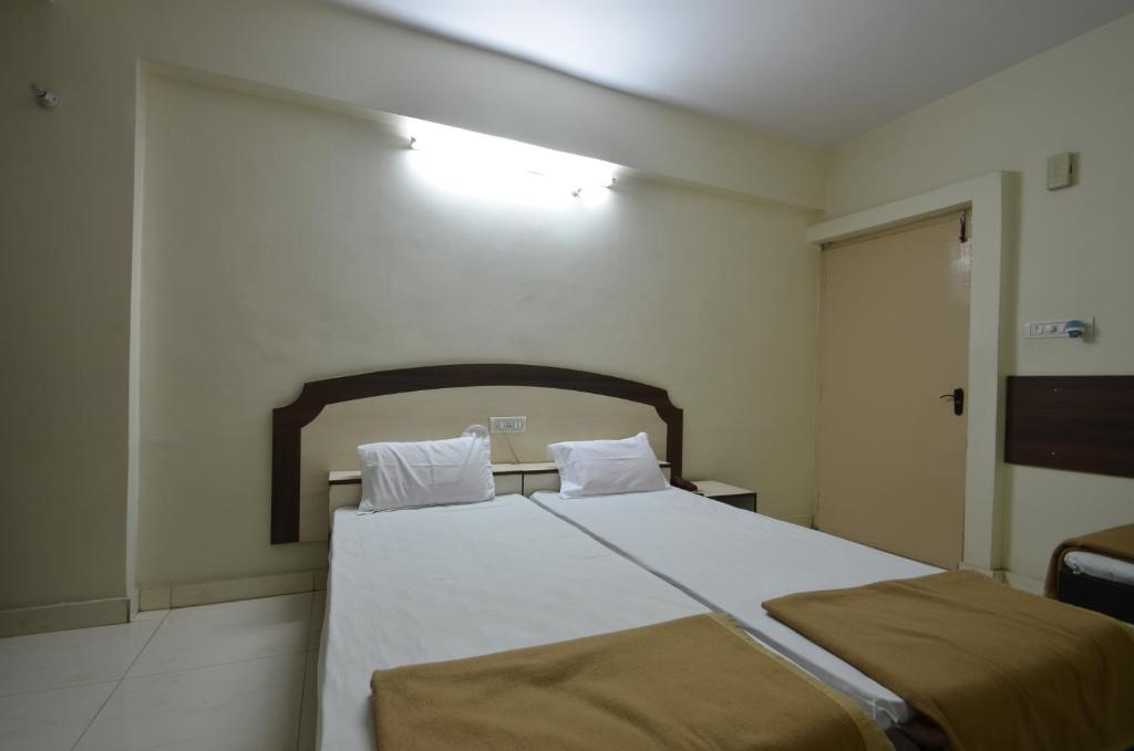 a bedroom with a large bed with white sheets at Hotel Maya Deluxe in Hyderabad