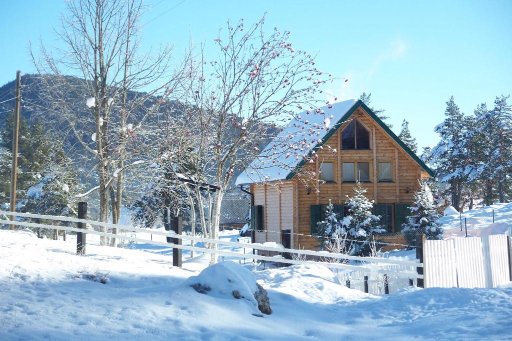 ein schneebedecktes Holzhaus mit einem Zaun in der Unterkunft Kuca u borju - House in pines in Žabljak
