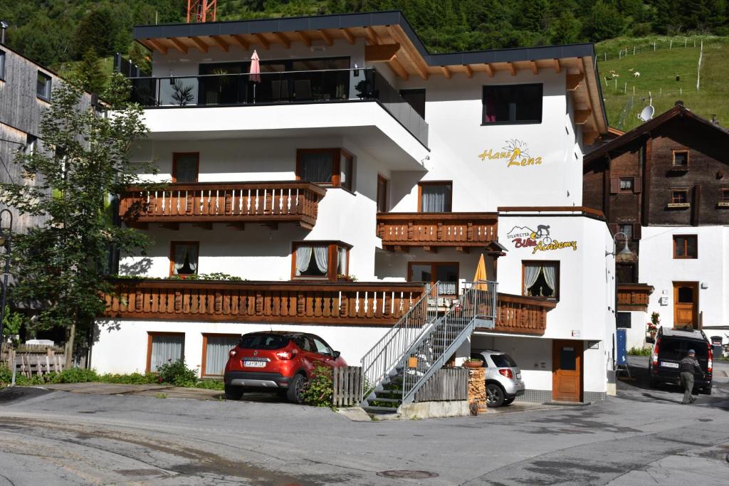 a large white building with a staircase in a parking lot at Pension Lenz in Ischgl