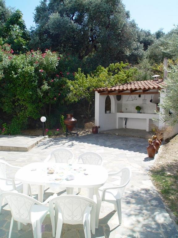 a patio with white tables and chairs and a building at Villa Maro in Skopelos Town