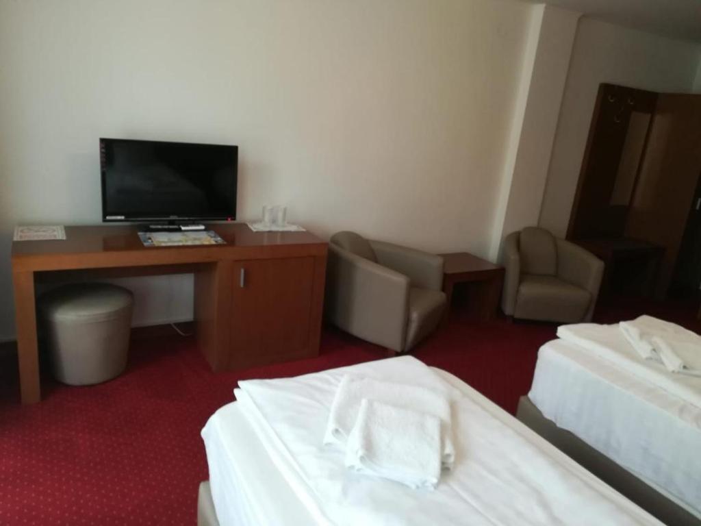 um quarto de hotel com duas camas e uma secretária e uma televisão em Hotel Dennis em Mediaş